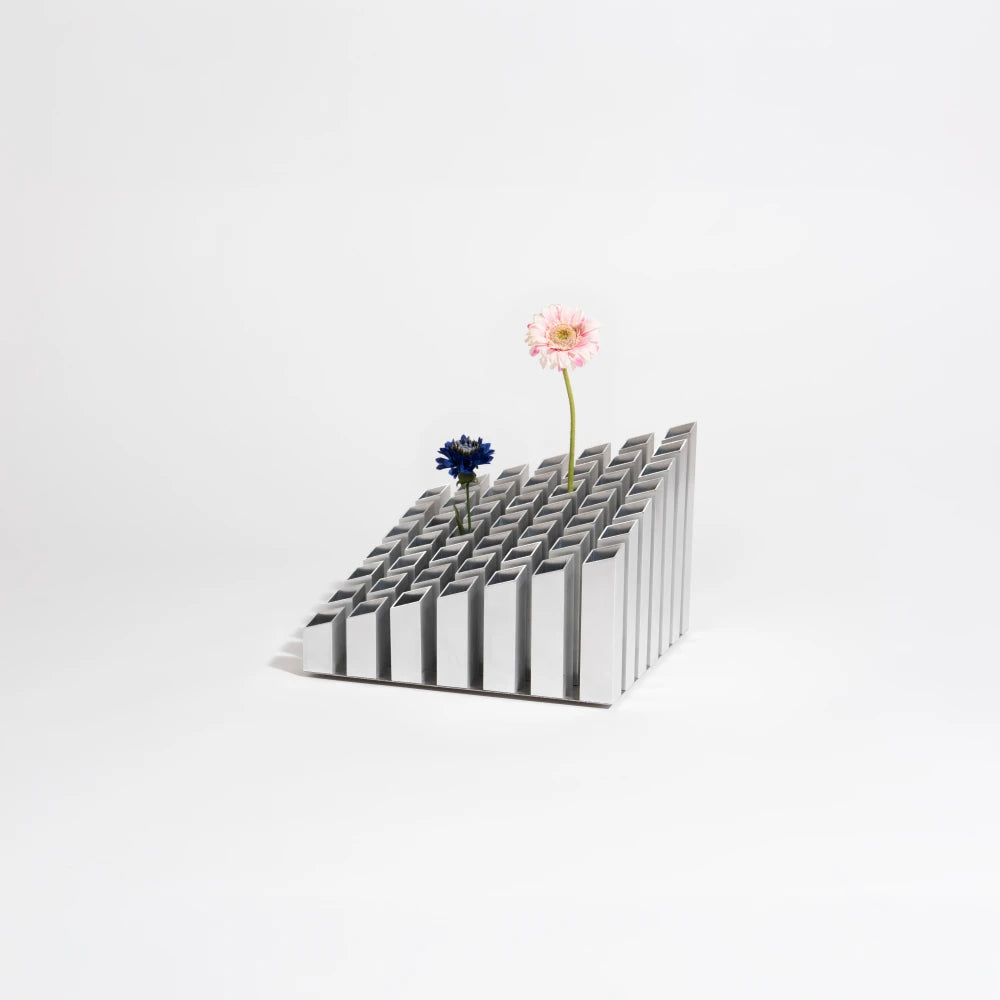 Cinquante decorative object by Malvin Gaborit in a silver finish, displayed with two flowers against a white background.